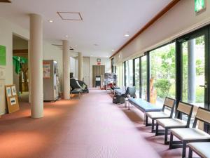 una zona de espera de un hospital con sillas y ventanas en momijigawa onsen, en Naka
