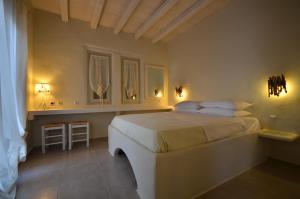 a bedroom with a large white bed with two mirrors at Portes Houses in Koufonisia