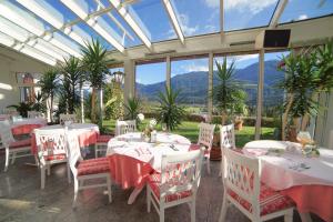 einen Wintergarten mit Tischen und Stühlen und einer Glasdecke in der Unterkunft Hotel Glocknerhof in Berg im Drautal