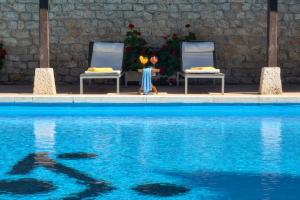 a swimming pool with two chairs and a statue of a woman at Parador de Chinchón in Chinchón