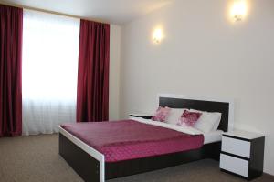 a bedroom with a large bed with red curtains at Elektron Hotel in Novosibirsk