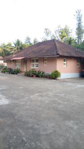 a pink house with a parking lot in front of it at StaySimple Spicefarm in Somvārpet