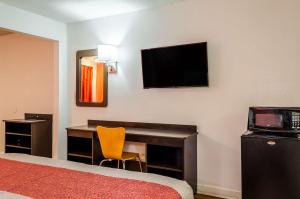 a hotel room with a desk and a television on the wall at Motel 6-Saraland, AL in Saraland