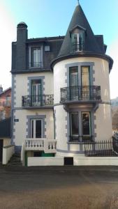 une grande maison blanche avec un toit noir dans l'établissement La Tour Pom'Pin, à La Bourboule