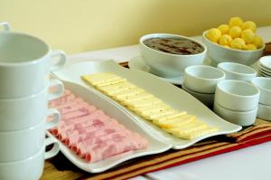 a tray of meats and cheese on a table with cups at Seven Machupicchu in Machu Picchu