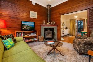 a living room with a green couch and a fireplace at Allambee in Katoomba