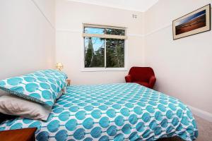 a bedroom with a bed and a red chair at Allambee in Katoomba