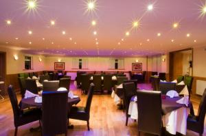 uma sala de jantar com mesas e cadeiras e luzes no tecto em Haveli Hotel em Hensol