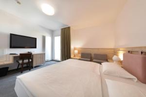 a hotel room with a large white bed and a desk at Hotel Mediteran in Zadar
