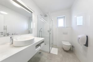 a white bathroom with a sink and a toilet at Hotel Mediteran in Zadar