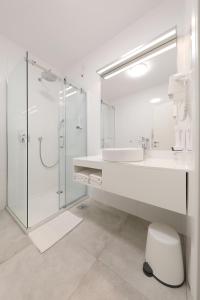 a white bathroom with a sink and a shower at Hotel Mediteran in Zadar