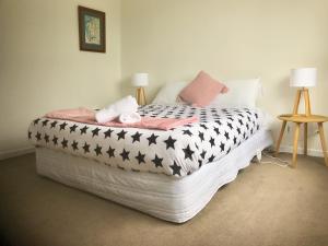 a bedroom with a bed with black and white comforter at Sycamore Villa, 2 bedroom apartment in Dunedin