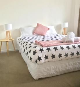 a bed with a black and white comforter on it at Sycamore Villa, 2 bedroom apartment in Dunedin +10 photos