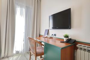 a hotel room with a desk with a television on a wall at Hotel Mediteran in Zadar
