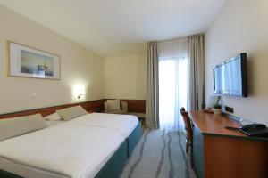 a hotel room with a bed and a desk and a television at Hotel Mediteran in Zadar