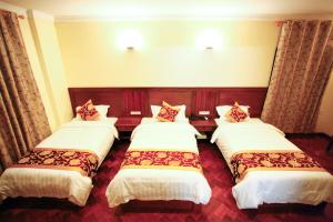 ein Hotelzimmer mit 3 Betten in einem Zimmer in der Unterkunft The Home Hotel in Mandalay