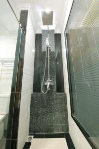baño con ducha y puerta de cristal en The Home Hotel en Mandalay