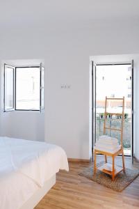 um quarto branco com uma cama e um banco de madeira em Casas de Mar - Búzio em Olhão
