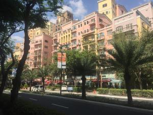 a large building with palm trees in front of a street at Venice, Mckinley Hill BGC in Manila