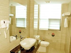 a bathroom with a sink and a toilet and a mirror at GreenTree Inn Anhui Hefei Mengcheng Road Beierhuan Express Hotel in Hefei