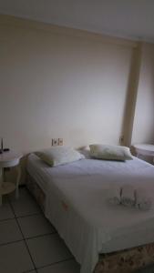 1 dormitorio con 1 cama blanca y 2 almohadas en Porto de Iracema - 611 Frente mar, en Fortaleza