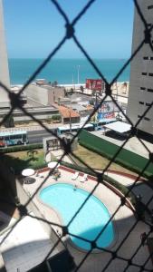 a view of a swimming pool from a chain link fence at Porto de Iracema - 611 Frente mar in Fortaleza