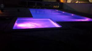 a swimming pool with purple lighting in a dark room at Kharisma Hotel in Mamaia Nord