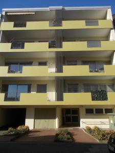 a tall yellow building with a person on the balcony at FeWo Bonnita - Nähe UN-Campus u. WCCB in Bonn