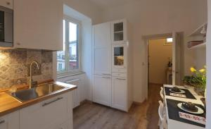 a kitchen with white cabinets and a sink at Casa della nonna sulla francigena in Campagnano di Roma