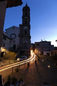 un edificio con una torre del reloj con un coche en una calle en La casa della nonna sulla francigena, en Campagnano di Roma