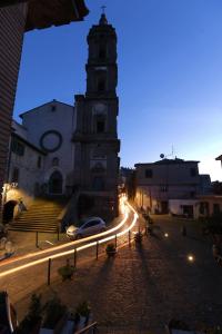 a building with a clock tower with a car on a street at Casa della nonna sulla francigena in Campagnano di Roma