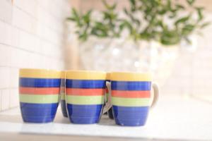 trois tasses rayées colorées assises sur une étagère dans l'établissement Green Point Home Chios, à Vrontádos