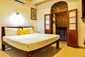 a bedroom with a bed with yellow pillows at Fort Sapphire in Galle