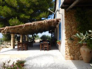a patio with tables and chairs and a straw roof at Agriturismo Case Sgaraglino in Marinella di Selinunte