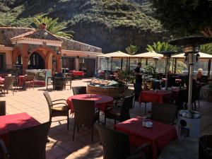 a restaurant with tables and chairs and a man standing in the background at La Villa in Mogán
