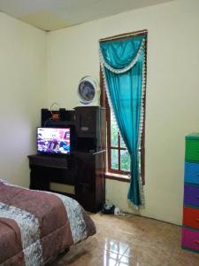 a bedroom with a bed and a television and a window at West Surabaya Homey in Surabaya