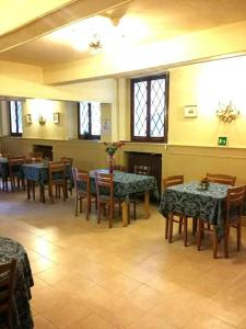 una sala da pranzo con tavoli, sedie e finestre di Hotel Ariosto centro storico a Reggio Emilia