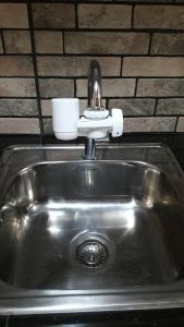a stainless steel sink with a cup on top of it at The Treehouse A @ Trees Residences in Manila
