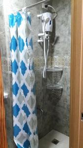 a shower with a blue and white shower curtain in a bathroom at The Treehouse A @ Trees Residences in Manila