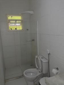 baño blanco con aseo y ventana en Hotel Pousada Papaya Verde en Salvador
