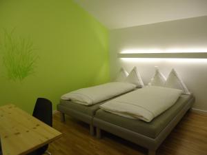 a green room with a bed with pillows on it at Hotel Alte Gärtnerei in Härkingen