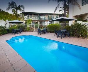 una piscina con mesas y sillas y un edificio en Windsor Lodge, en Perth