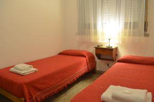 een kamer met 2 bedden met rode lakens en een raam bij Hotel Marino in Villa Gesell