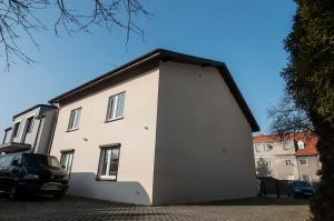 a white house with a car parked next to it at Apartamenty na Dębcu in Poznań