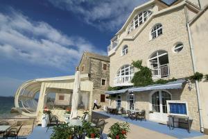 a large building with tables and chairs next to the water at Aparthotel Marina in Primošten