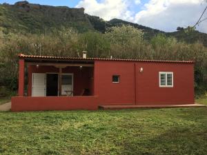a red house with a hill in the background at Villa Rafael in Vega de San Mateo