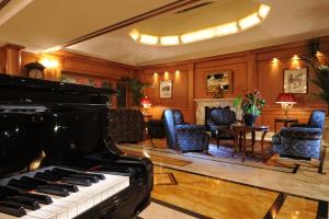 a room with a piano and a living room with chairs at Hotel Manzoni in Milan