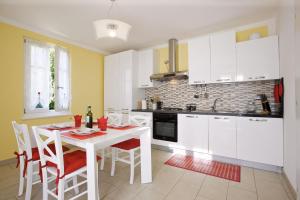 a kitchen with white cabinets and a white table and chairs at La Tranquillità in Oggebbio