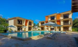 einem Pool mit Stühlen und Sonnenschirmen vor einem Gebäude in der Unterkunft Caribbean Diamond Boutique Hotel in Sosúa