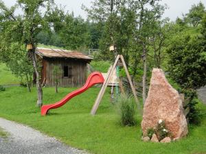 ローファーにあるFerienwohnung Brennerbauerの芝生の滑り台と岩盤がある遊び場